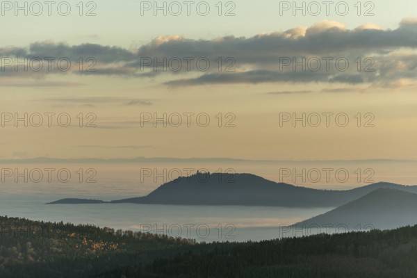 The landscape of hills and mountains is illuminated by a gentle sunset. Sea of fog in distance inspire peaceful and serene atmosphere. Bas Rhin, Alsace, France