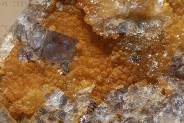 Shiny crystals of blue and orange color can be seen in this mineral formation. They are sparkling and show interesting textures in a natural setting