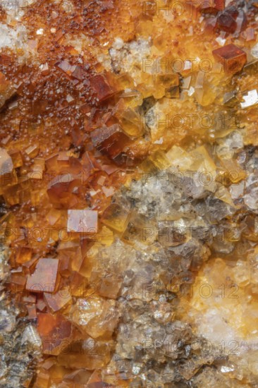 Shiny crystals of blue and orange color can be seen in this mineral formation. They are sparkling and show interesting textures in a natural setting