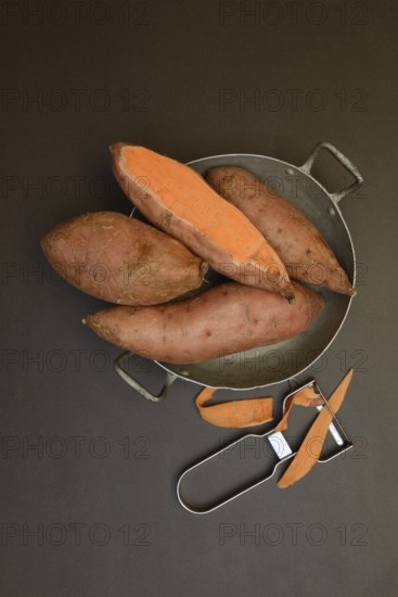 Sweet potatoes in skin with potato peeler, Ipomoea batatas