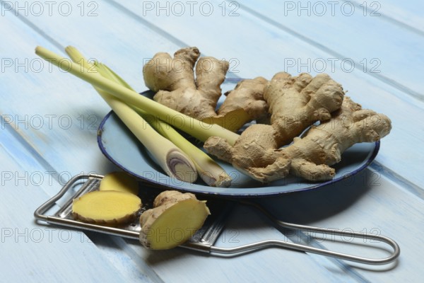 Ginger tubers and lemongrass on plate, grater with ginger pieces