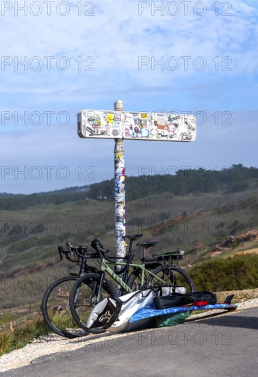 Sticker-covered sign with bicycles and surfboards, Nazaré, Portugal