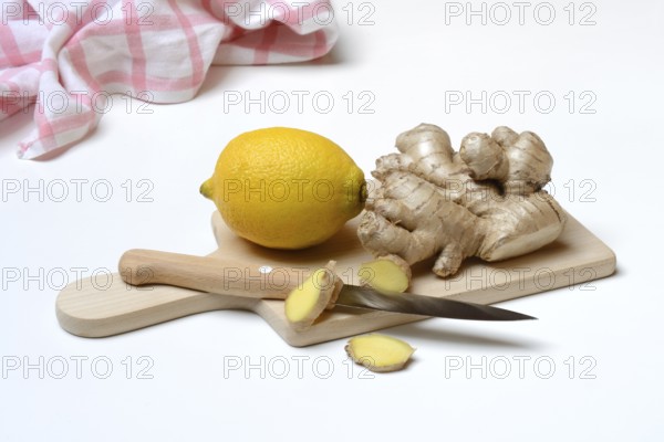 Ginger root and lemon on cutting board with knife, ginger slices, Zingiber officinale