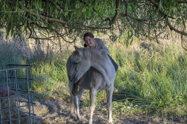Young girl sitting on her horse in the pasture, Othenstorf, Mecklenburg-Western Pomerania, Germany
