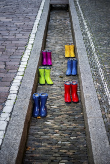 Colourful rubber boots in dry watercourse, Freiburg im Breisgau