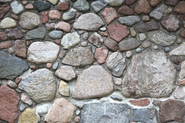 Rustic stone wall made of uneven natural stones in different colors