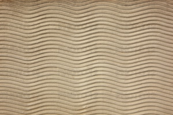 Beige sand surface with uniform wavy lines