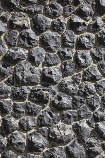 Detail of a wall of black, irregular rocks