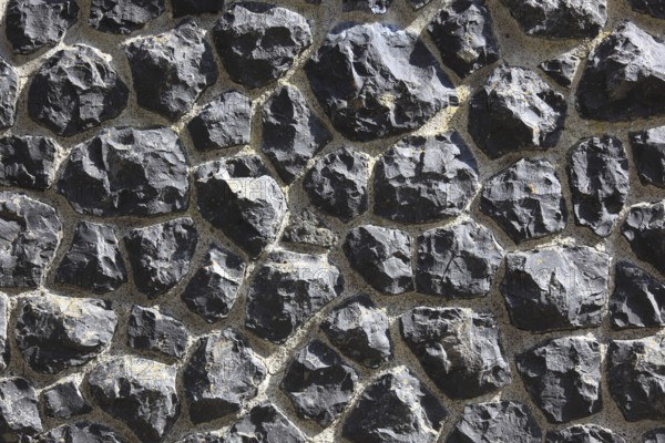 Rough wall of black rocks with distinctive structure