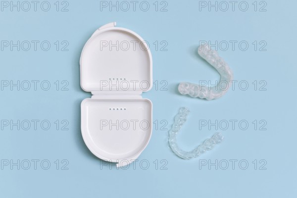 Customized transparent dental teeth bite guard clear aligners for lower jaw in white case on blue background
