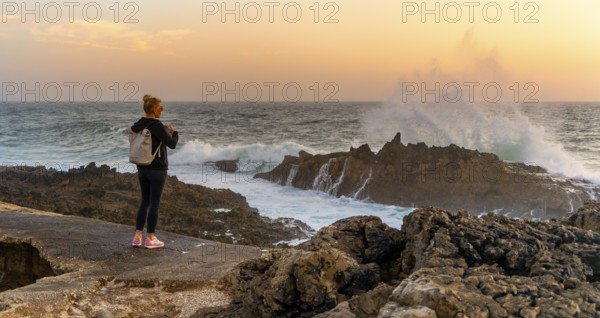 Young tourist standing on the coast of Farol de Cabo Raso lighthouse, SÃ£o Bras de Sanxete fortress, Cascais, Portugal
