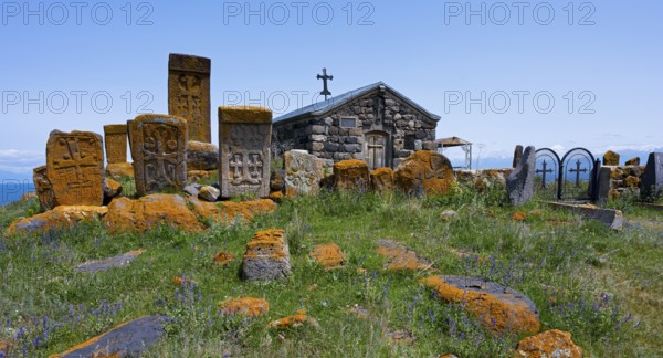 Historic chapel and tombs with stone crosses on a grassy hill, khachkars at the chapel of the Holy Cross and cemetery near Noratus, Sarukhan, Lake Sevan, Gegharkunik province, Armenia