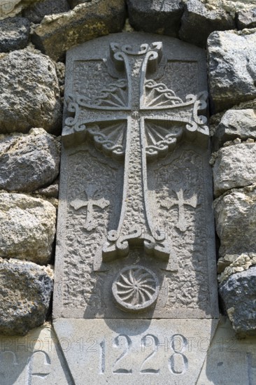 Historic stone cross with engravings and decorated architecture embedded in a stone wall, Chapel of the Holy Cross, Sarukhan, Lake Sevan, Gegharkunik Province, Armenia