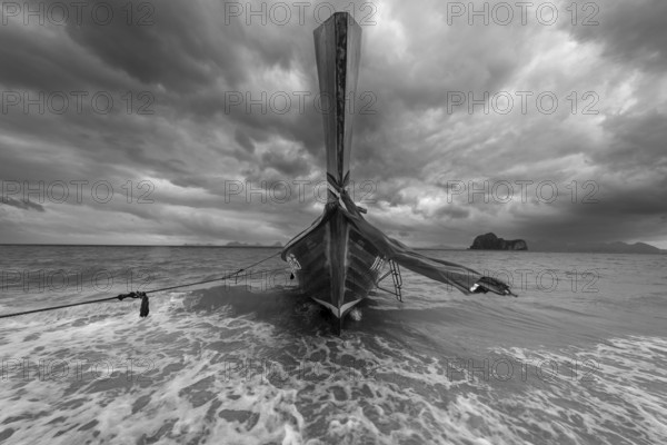 Longtail boat on the beach with dark rain clouds behind it, Koh Ngai island, Andaman Sea, Satun province, southern Thailand, Thailand