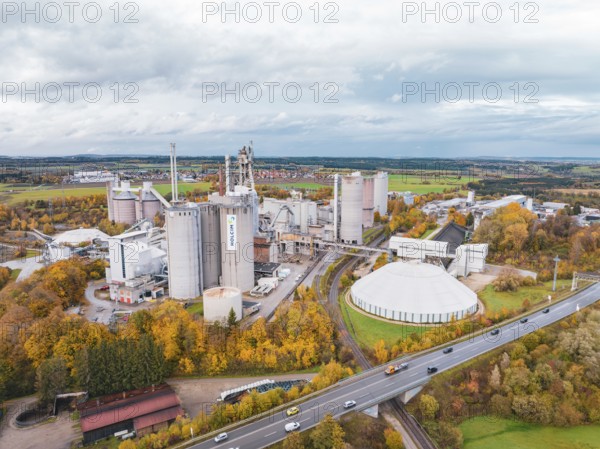 A bird's eye view of a large industrial complex surrounded by colorful autumn trees and roads