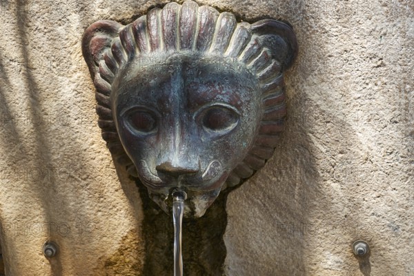 A bronze lion head sculpture that serves as a fountain and steers water in an ancient setting, Ancient Stadium, Nemea, Peloponnese, Greece