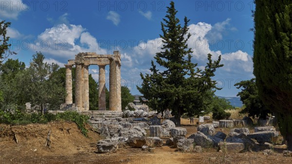 Ruins of an ancient temple against a blue sky with trees and scattered stones, Ancient Zeus Sanctuary, Nemea, Peloponnese, Greece