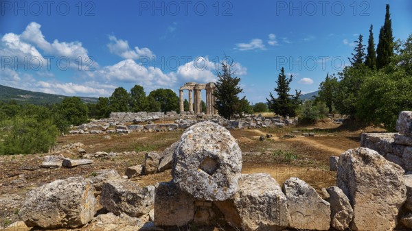 Ancient temple columns in an open field with surrounding trees and mountains in the background, Ancient Zeus Sanctuary, Archaeological Site, Nemea, Peloponnese, Greece