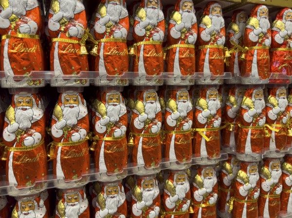 Display on the shelf of chocolate Santa Claus chocolate Santa Claus Santa Claus Santa Claus Santa Claus chocolate Santa Claus chocolate Santa Claus chocolate lice Santa Claus chocolate lice Santa Claus in color red of red staniol paper made of chocolate arranged like army of Santa Claus, Germany