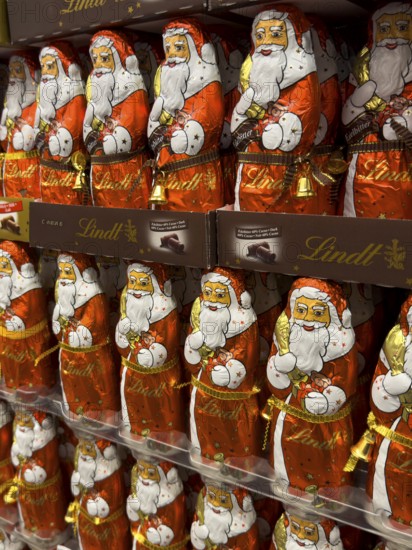 Display on the shelf of chocolate Santa Claus chocolate Santa Claus Santa Claus Santa Claus Santa Claus chocolate Santa Claus chocolate Santa Claus chocolate lice Santa Claus chocolate lice Santa Claus in color red of red staniol paper made of chocolate arranged like army of Santa Claus, Germany