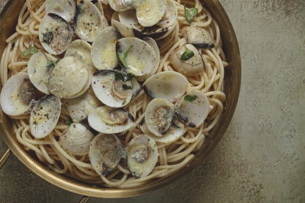 Spaghetti with vongole clams, in cream sauce, carbonara, in a brass pan, homemade, top view, no people