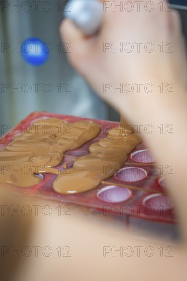Close-up of a hand pouring liquid chocolate into a mold, Christmas baking, Haselstaller Hof, Wildberg, Calw district, Germany