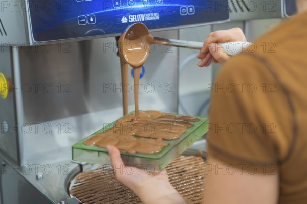 Chocolate is filled into flat molds by a person from a device, Christmas baking, Haselstaller Hof, Wildberg, Calw district, Germany
