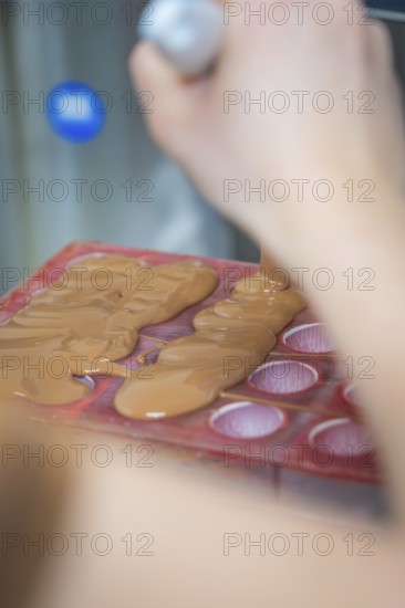 Close-up of liquid chocolate being poured into a chocolate mold, Christmas baking, Haselstaller Hof, Wildberg, Calw district, Germany