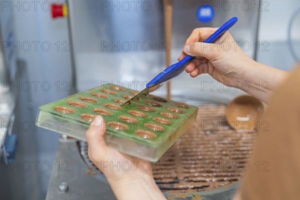 Chocolate mold is filled with chocolate by one hand using a kitchen tool, Christmas baking, Haselstaller Hof, Wildberg, Calw district, Germany