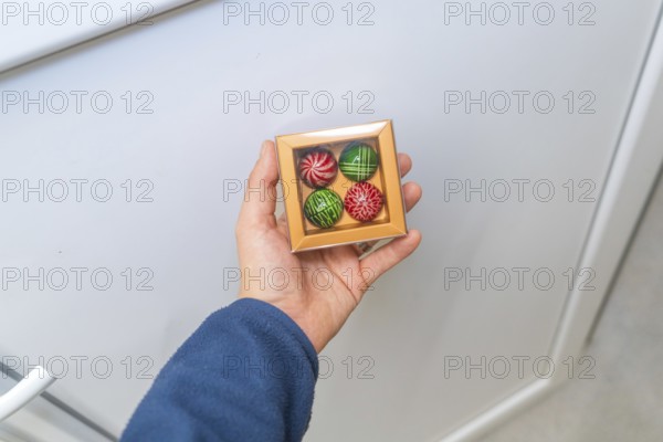 Person holding a chocolate box with patterned chocolates on a light background, Christmas baking, Haselstaller Hof, Wildberg, Calw district, Germany