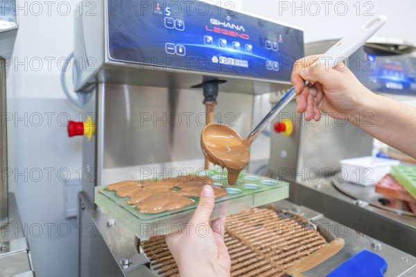 Chocolate is poured into molds from a machine with a ladle, Weihnachtsbacken, Haselstaller Hof, Wildberg, Calw district, Germany