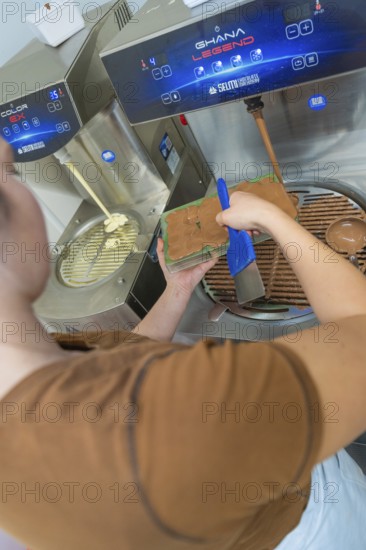Person uses a blue tool to fill chocolate into a mold at a tempering machine, Christmas baking, Haselstaller Hof, Wildberg, Calw district, Germany