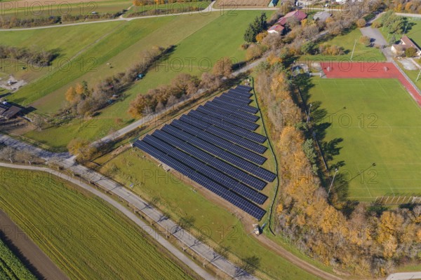Aerial view of a solar system next to a soccer field in a rural autumn landscape, PV Freifaechenanlage construction, Weil der Stadt, Germany