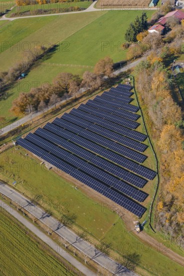 Orderly solar energy field next to fields and a small village from the air, Bau PV Freifaechenanlage, Weil der Stadt, Germany