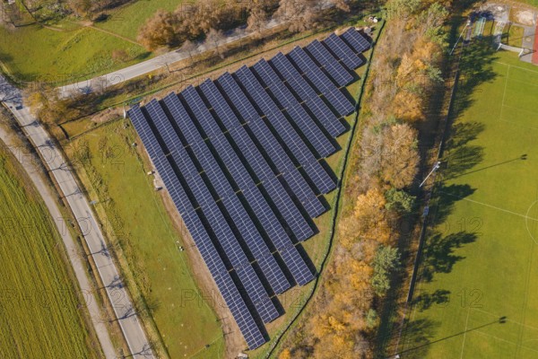 Aerial view of a solar plant surrounded by green fields and autumn trees, PV Freifaechenanlage construction, Weil der Stadt, Germany