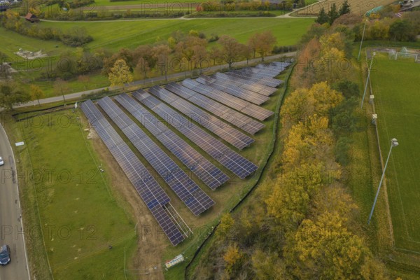 Solar system on a green area with autumn trees in the background, Bau PV Freifaechenanlage, Weil der Stadt, Germany
