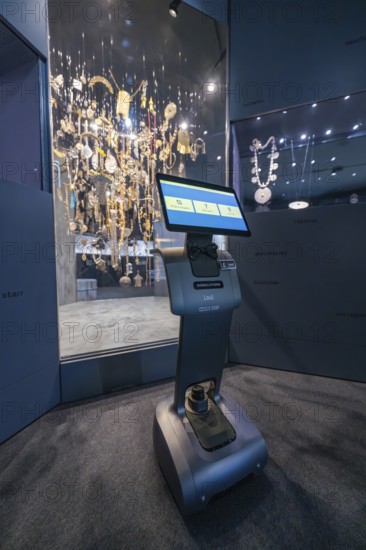 An interactive robot stands in front of an illuminated display case with jewelry in the museum, robotic personality Roboloutions in the jewelry museum, Pforzheim, Germany