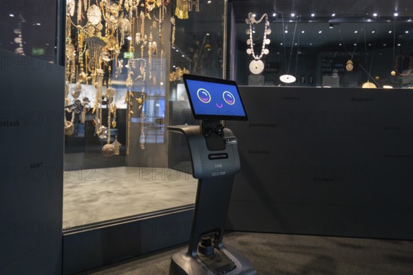 Smiling robot in front of display cabinet with jewelry in museum, robotic personality Roboloutions in jewelry museum, Pforzheim, Germany