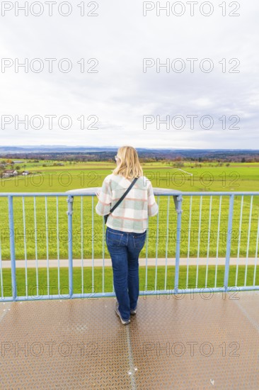 Woman looking out over an extensive green field from the tower, DÃ¼rrenmettstetten observation tower, Sulz am Neckar, Germany