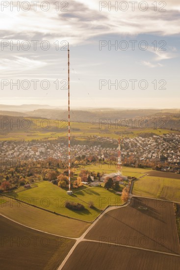 A tall radio tower rises above an autumn landscape with a small town in the background, MÃ¼hlacker, Enzkreis, Germany