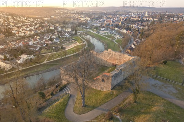 A historic castle overlooks a river and urban structures at dusk, MÃ¼hlacker, Enzkreis, Germany