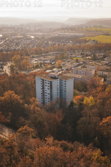 A high-rise residential building rises between autumn trees in an urban area, MÃ¼hlacker, Enzkreis, Germany