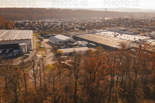 Industrial plant on the outskirts of town, surrounded by autumnal forest and light haze, MÃ¼hlacker, Enzkreis, Germany