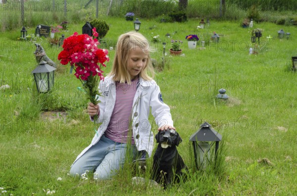 Grieving blonde 7-year-old girl at her dog's grave at pet cemetery in Ystad, SkÃ¥ne County, Sweden, Scandinavia