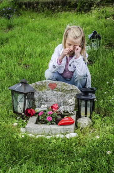 Grieving blonde 7-year-old girl at her cat's grave at pet cemetery in Ystad, SkÃ¥ne County, Sweden, Scandinavia