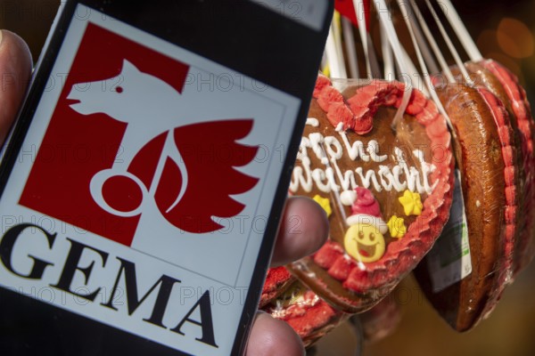 (photo montage) Smartphone with opened GEMA logo in front of a stand at a Christmas market