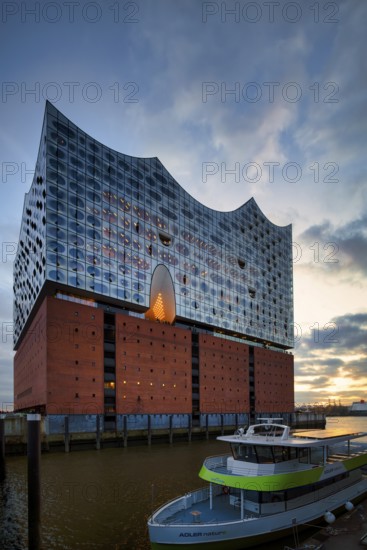 Excursion boat in front of the glass faÃ§ade of the Elbe Philharmonic Hall, Elphie, plaza, viewing platform, terrace, Free and Hanseatic City of Hamburg, evening light, Germany