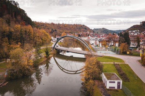 Beautiful bridge in autumn landscape, framed by colorful trees and reflected in water, Sulz am Neckar, Germany