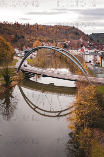 Bridge over a river in an autumn landscape, houses in the background and reflection in the water, Sulz am Neckar, Germany