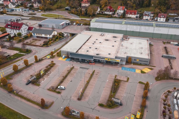 Large supermarket with adjacent parking lot and surrounding residential buildings in an autumn city scene, Sulz am Neckar, Germany